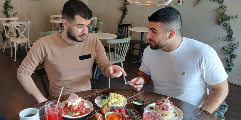Nikola och Dilan diskuterar maten som står på bordet framför dem.