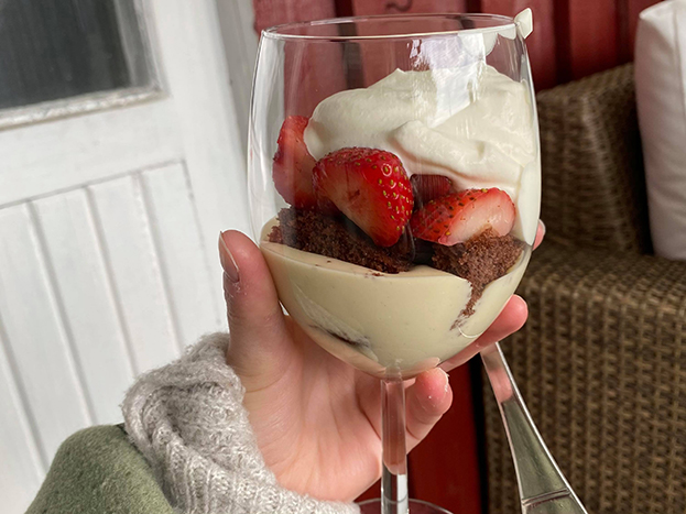 På bilden ser vi ett brett vinglas med desserten i. Först kommer ett lager av vaniljkräm, sedan en brun chokladbottenbit, sedan lite jordgubbar och sist en massa grädde. 